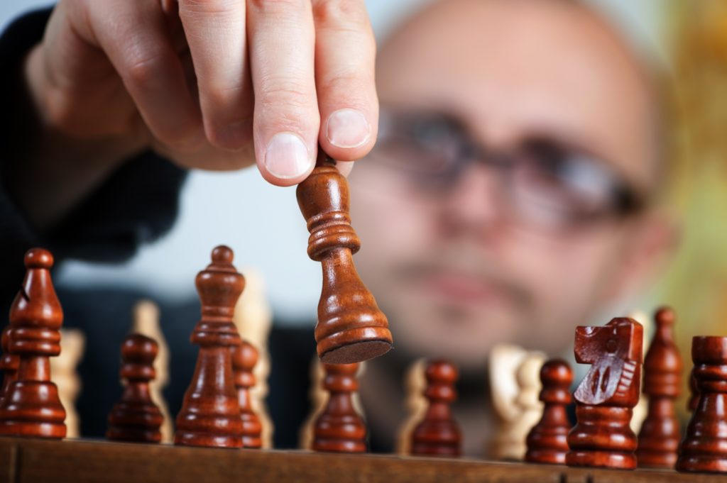 Mann spielt mit Schachfiguren als Symbol für imaginative Familienaufstellung